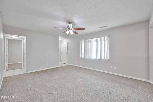 carpeted empty room with baseboards, a ceiling fan, a textured ceiling, and visible vents