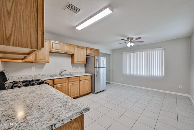 kitchen featuring a sink, light countertops, range, freestanding refrigerator, and visible vents