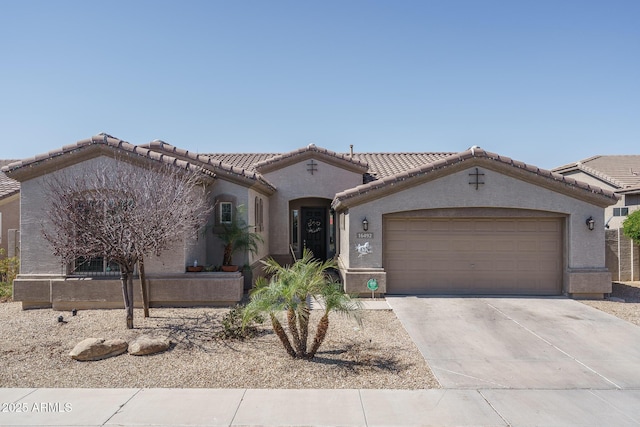 mediterranean / spanish house featuring concrete driveway, a tiled roof, a garage, and stucco siding