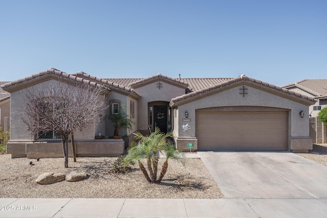 mediterranean / spanish house featuring concrete driveway, a tiled roof, a garage, and stucco siding