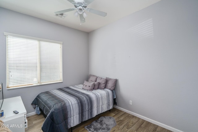 bedroom with a ceiling fan, wood finished floors, visible vents, and baseboards