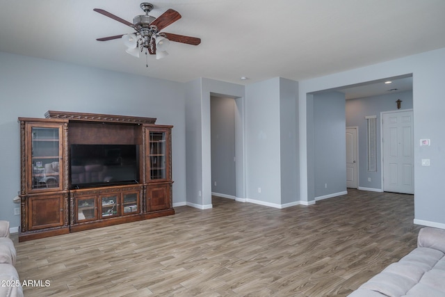 unfurnished living room featuring light wood-style flooring, a ceiling fan, and baseboards