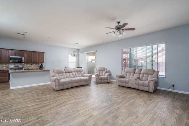 living room with light wood-type flooring, visible vents, a wealth of natural light, and ceiling fan with notable chandelier