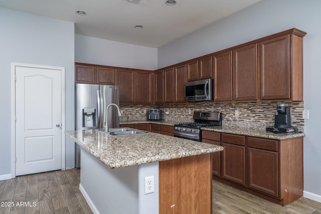 kitchen featuring a sink, decorative backsplash, light wood-style floors, and appliances with stainless steel finishes