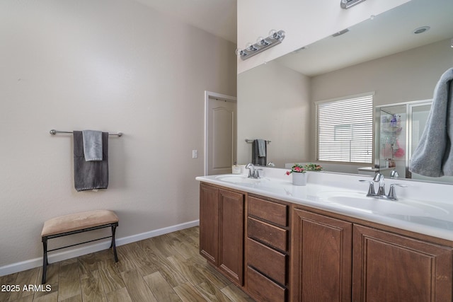 bathroom featuring double vanity, a shower stall, baseboards, and a sink