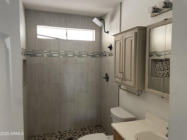 bathroom featuring tiled shower, vanity, and toilet