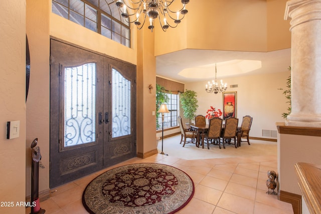 entryway featuring decorative columns, a notable chandelier, tile patterned floors, and french doors