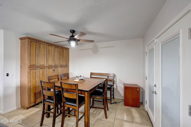 dining space with light tile patterned flooring, a textured ceiling, and baseboards