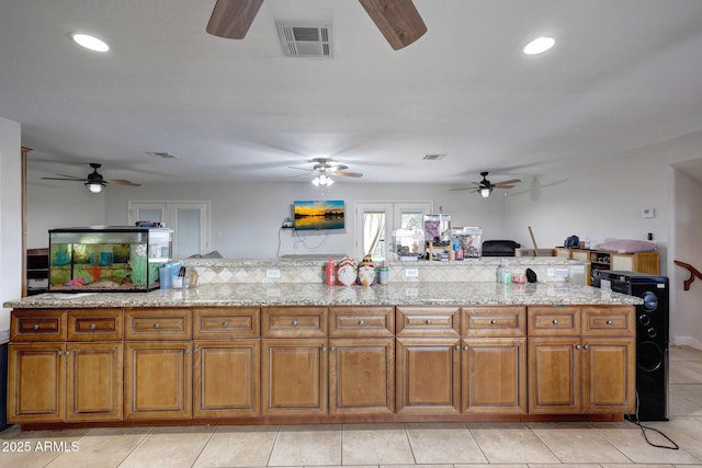 kitchen with brown cabinets, recessed lighting, visible vents, and light tile patterned flooring