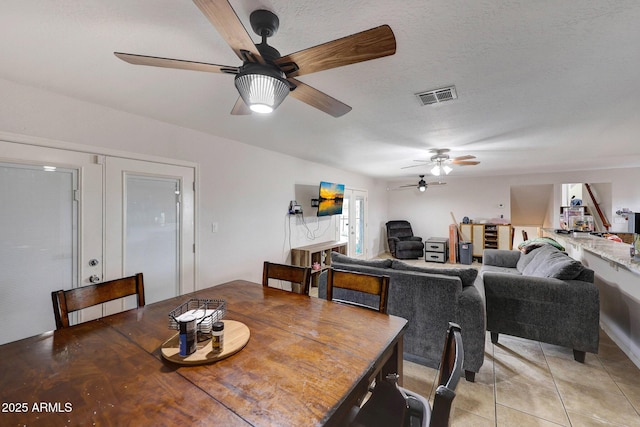 dining space featuring light tile patterned floors, a ceiling fan, visible vents, and a textured ceiling