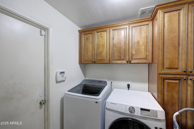 laundry room featuring visible vents, a textured ceiling, washing machine and clothes dryer, and cabinet space