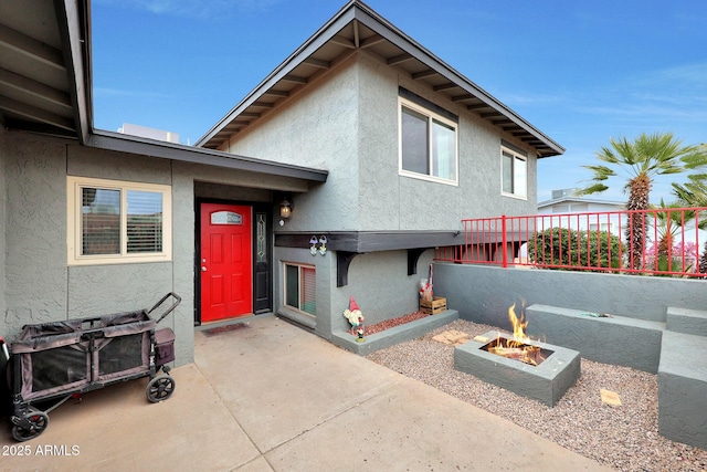 exterior space featuring an outdoor fire pit, a patio area, and stucco siding