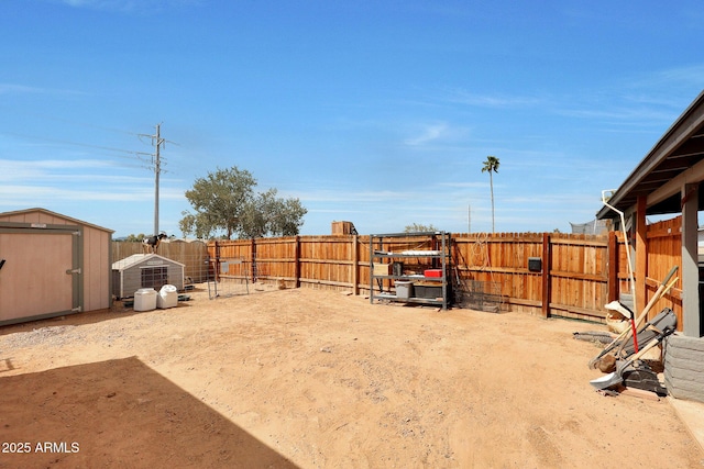 view of yard featuring a fenced backyard, a storage unit, and an outdoor structure