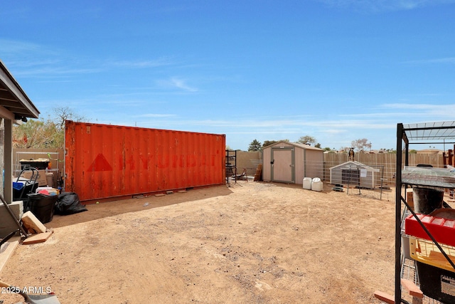 view of yard featuring an outbuilding, a storage unit, and fence