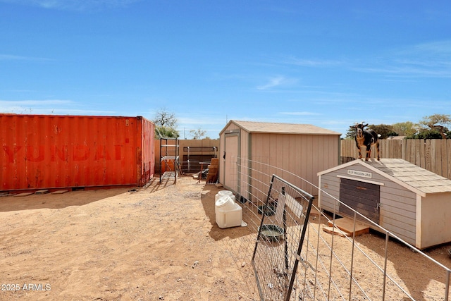 view of side of property with a fenced backyard, an outdoor structure, and a storage shed