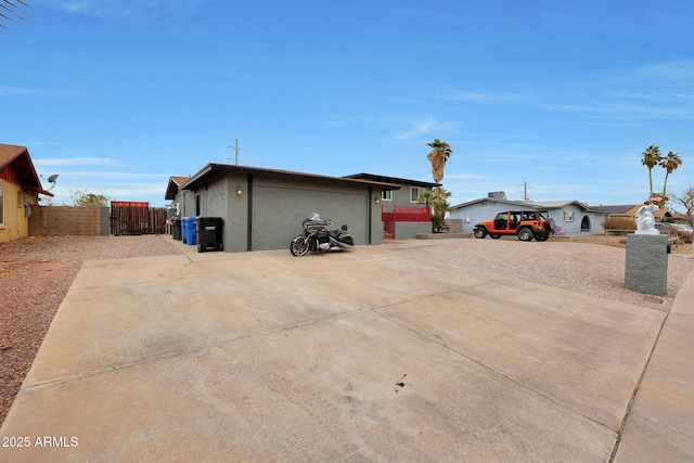 view of home's exterior with driveway, an attached garage, fence, and stucco siding