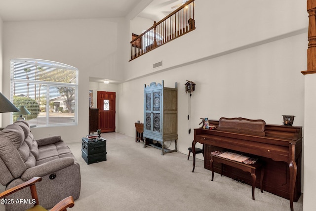 living area featuring high vaulted ceiling, visible vents, and light colored carpet