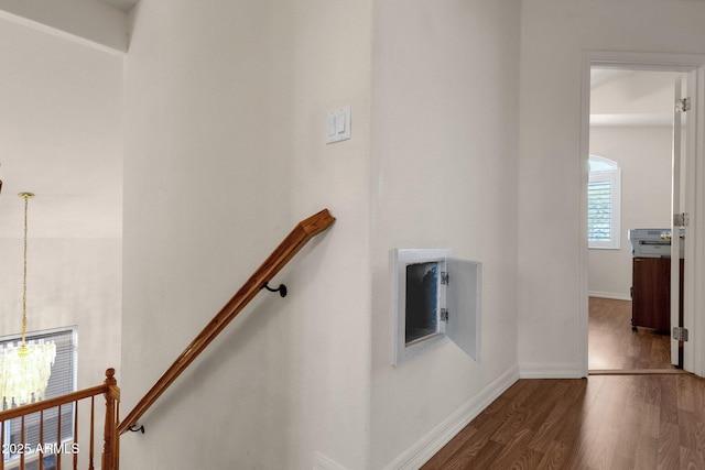 stairway featuring baseboards, wood finished floors, and a notable chandelier