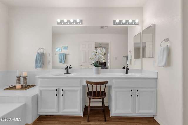 full bathroom featuring double vanity, a garden tub, and a sink