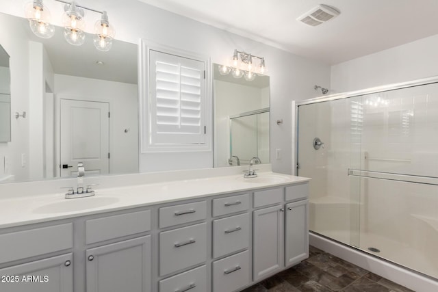 bathroom featuring visible vents, a sink, a shower stall, and double vanity