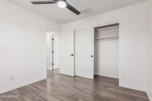 unfurnished bedroom with baseboards, visible vents, a ceiling fan, wood finished floors, and a closet