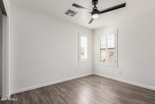 empty room featuring a ceiling fan, baseboards, visible vents, and wood finished floors