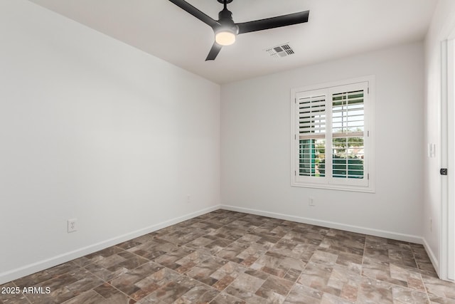 spare room featuring a ceiling fan, stone finish floor, visible vents, and baseboards