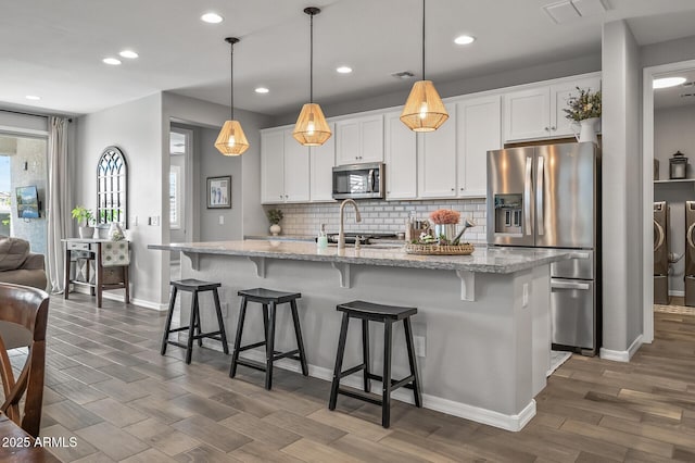 kitchen with backsplash, visible vents, washer and dryer, appliances with stainless steel finishes, and dark wood-style flooring