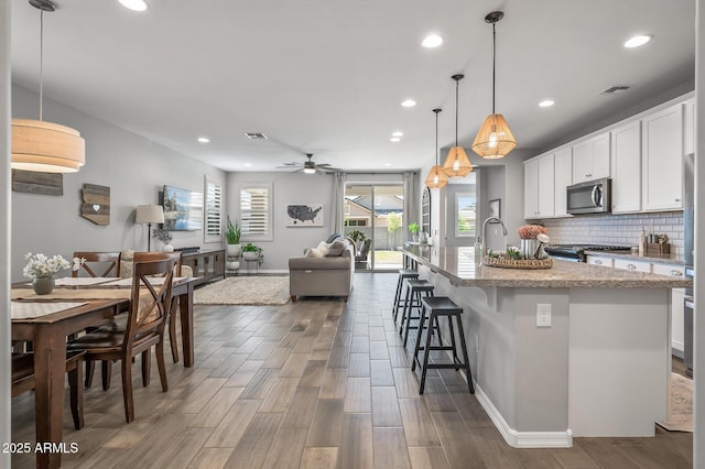 kitchen with wood finished floors, baseboards, stainless steel microwave, and stove