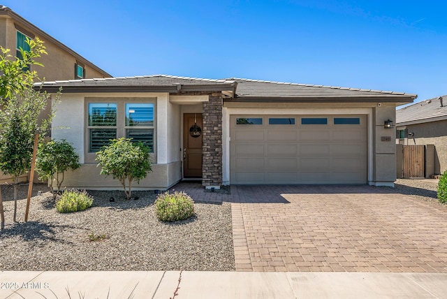 view of front of house with stucco siding, an attached garage, decorative driveway, and a tile roof