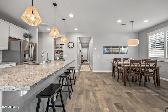kitchen featuring stainless steel fridge, wood finished floors, baseboards, and a sink