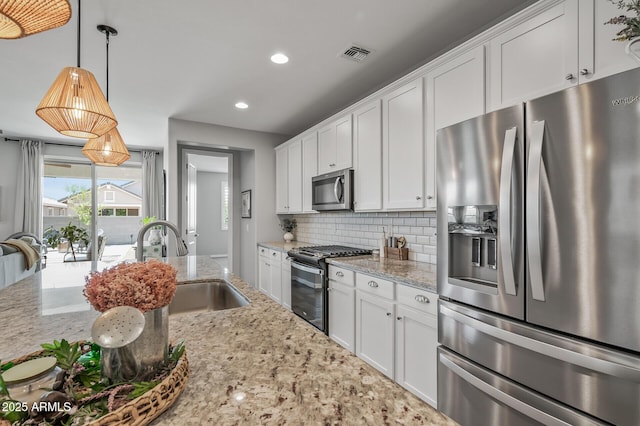 kitchen with decorative backsplash, white cabinetry, stainless steel appliances, and a sink