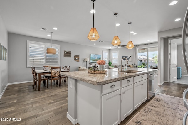 kitchen featuring white cabinets, a sink, a center island with sink, visible vents, and wood finished floors