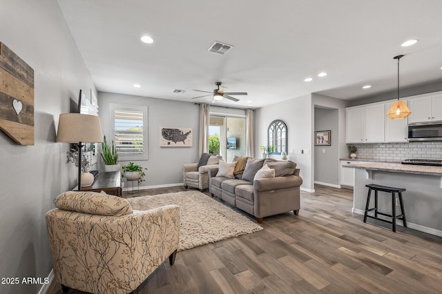 living area featuring baseboards, visible vents, recessed lighting, and dark wood-type flooring