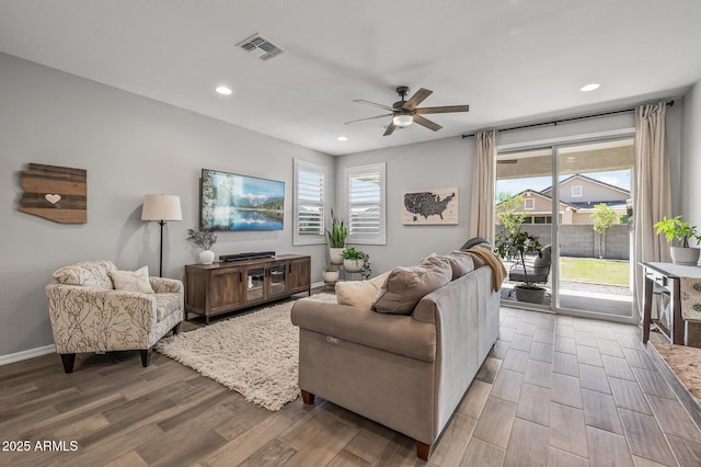 living area featuring wood finished floors, visible vents, a ceiling fan, and plenty of natural light