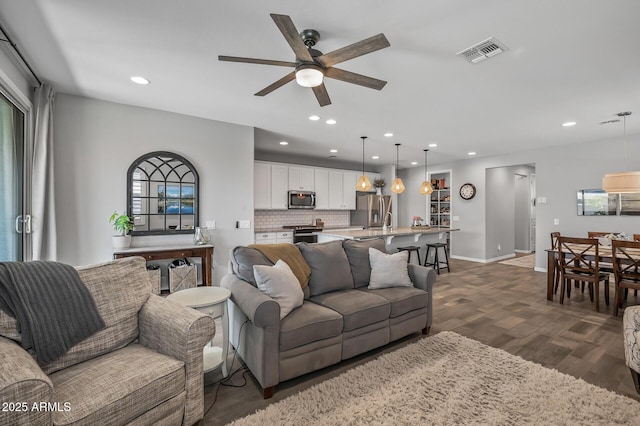living area with recessed lighting, visible vents, a ceiling fan, and dark wood-style flooring