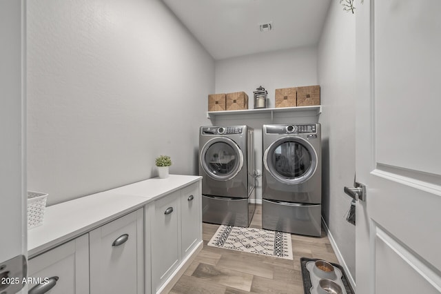 laundry area featuring washer and dryer, cabinet space, visible vents, and light wood-style flooring