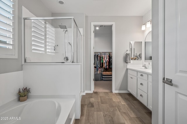 full bath featuring a shower stall, vanity, wood finished floors, and plenty of natural light