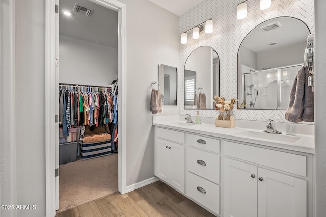 full bath featuring a shower stall, visible vents, wood finished floors, and a sink