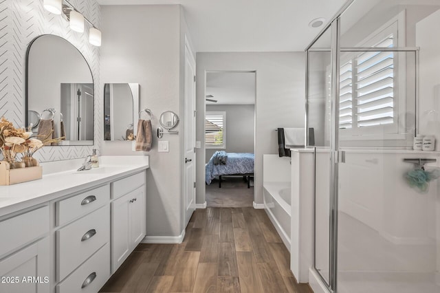 ensuite bathroom with a shower stall, baseboards, vanity, and wood finished floors