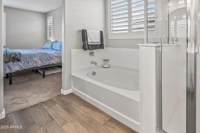 ensuite bathroom with a stall shower, baseboards, wood finished floors, a garden tub, and connected bathroom
