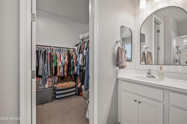 full bath with a walk in closet, vanity, and a shower with door