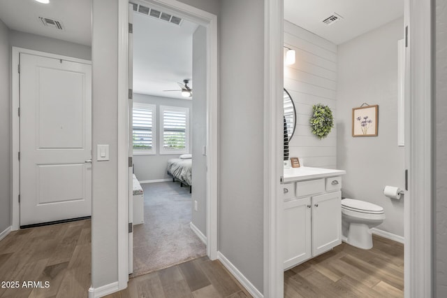 ensuite bathroom with wood finished floors, visible vents, toilet, and ceiling fan