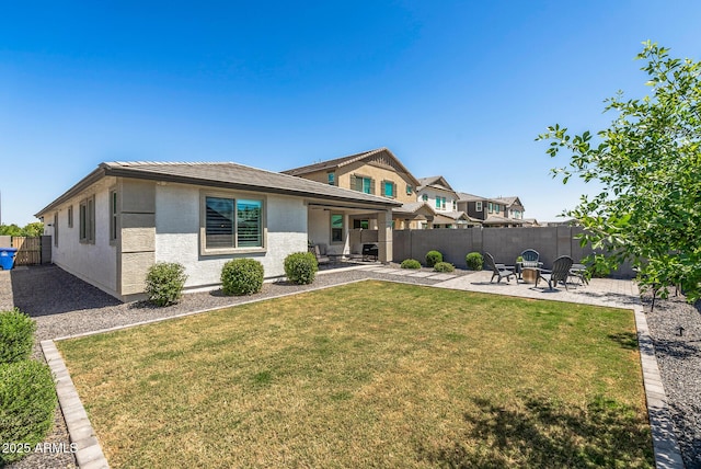 rear view of property with a fenced backyard, stucco siding, a patio area, and a lawn