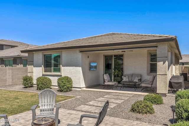 back of property with stucco siding, fence, an outdoor living space with a fire pit, and a patio