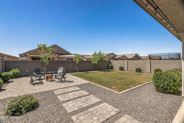view of yard with a fire pit, a fenced backyard, and a patio