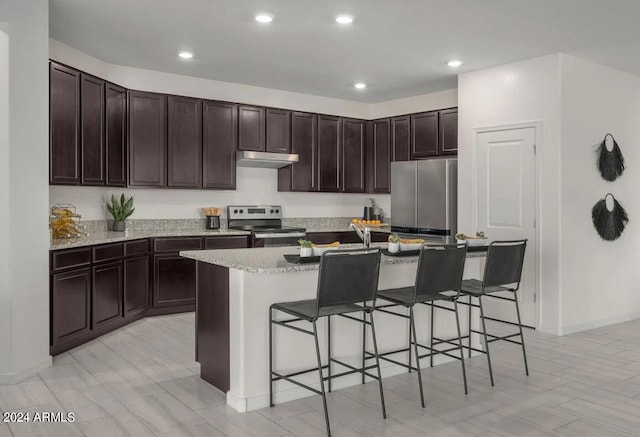 kitchen featuring an island with sink, a kitchen breakfast bar, appliances with stainless steel finishes, and dark brown cabinetry