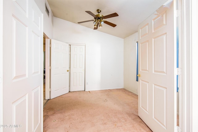 unfurnished bedroom featuring lofted ceiling, light colored carpet, a closet, and ceiling fan