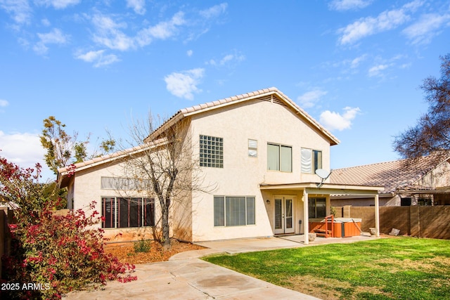 rear view of house featuring a yard, a hot tub, and a patio