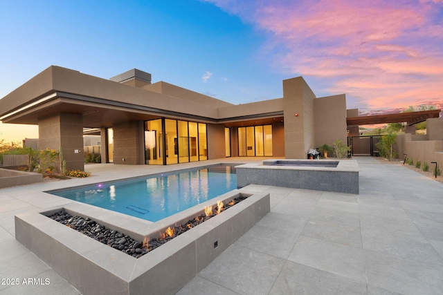10354 E Celestial Dr, Scottsdale, AZ 85262 - pool at dusk with an outdoor fire pit, a patio area, fence, and a pool with connected hot tub